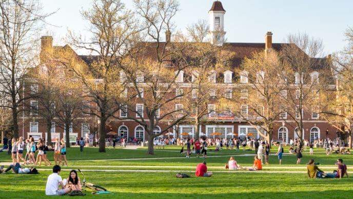URBANA, ILLINOIS - APRIL 17, 2016: Students walk and sit outside on Quad lawn of University of Illinois college campus in Urbana Champaign