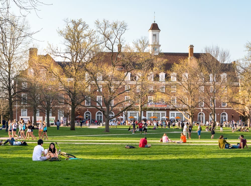 URBANA, ILLINOIS - APRIL 17, 2016: Students walk and sit outside on Quad lawn of University of Illinois college campus in Urbana Champaign