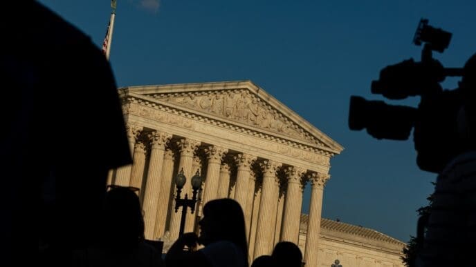 US Supreme Court Building in Washington, DC with Protestors' and TV Camera's black Silhouettes in Foreground during a Protest