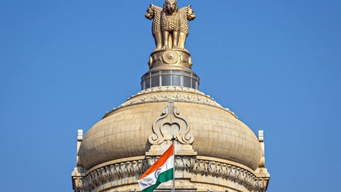 Close up image of dome of largest legislative building in India - Vidhan Soudha , Bangalore with nice blue sky background. Translation of text mentioned is Government work is God's work.