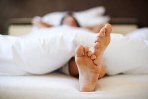 A beautiful woman is in bed, doing 'cricket feet' as she falls asleep.