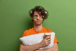 Close up on young man with a cup of coffee without being able to sleep