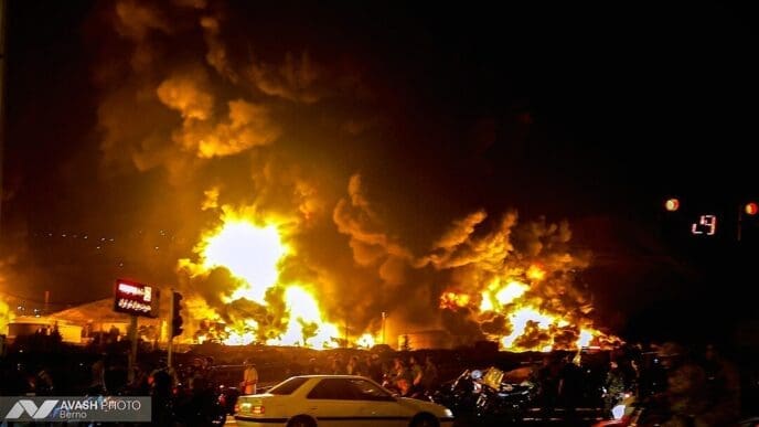 A photograph showing thick black smoke and flames rising from a damaged building in the aftermath of a reported Israeli attack on June 15, 2025.