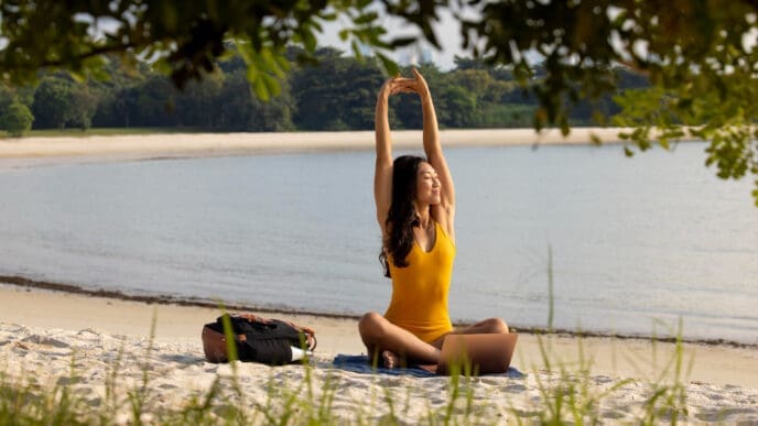 Full shot woman stretching and relaxing at the beach