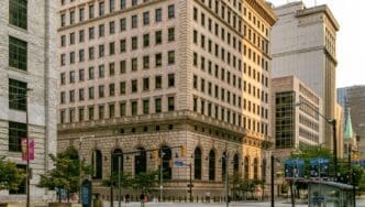 An oblique view of the historic Federal Reserve Bank of Cleveland, showcasing its grand neoclassical architecture, massive stone facade, and ornate details from a three-quarter angle.