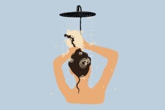 A stylized illustration of a person with dark hair seen from behind, washing their hair with shampoo lather under a shower head against a light blue background.