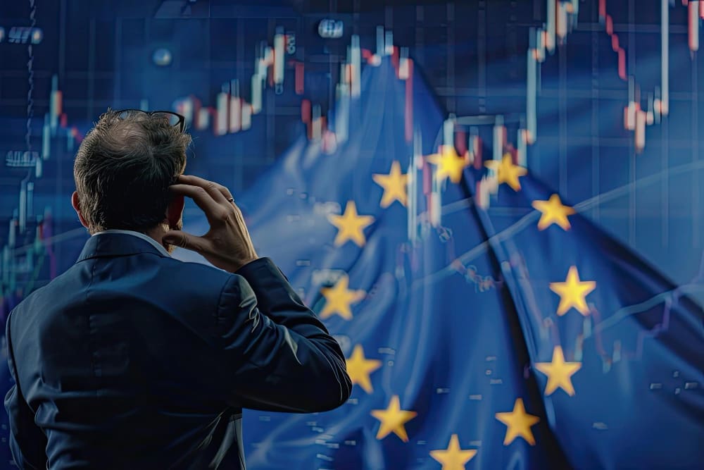 A man in a suit, seen from behind, stands with a hand to his head, looking at a volatile financial stock chart superimposed over a blurred European Union flag, symbolizing market analysis.