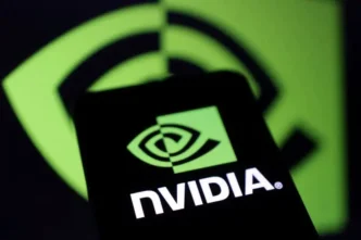 A smartphone displaying the bright green NVIDIA logo on its screen, held in front of a larger, blurred NVIDIA logo in the background, creating a repeated visual motif.