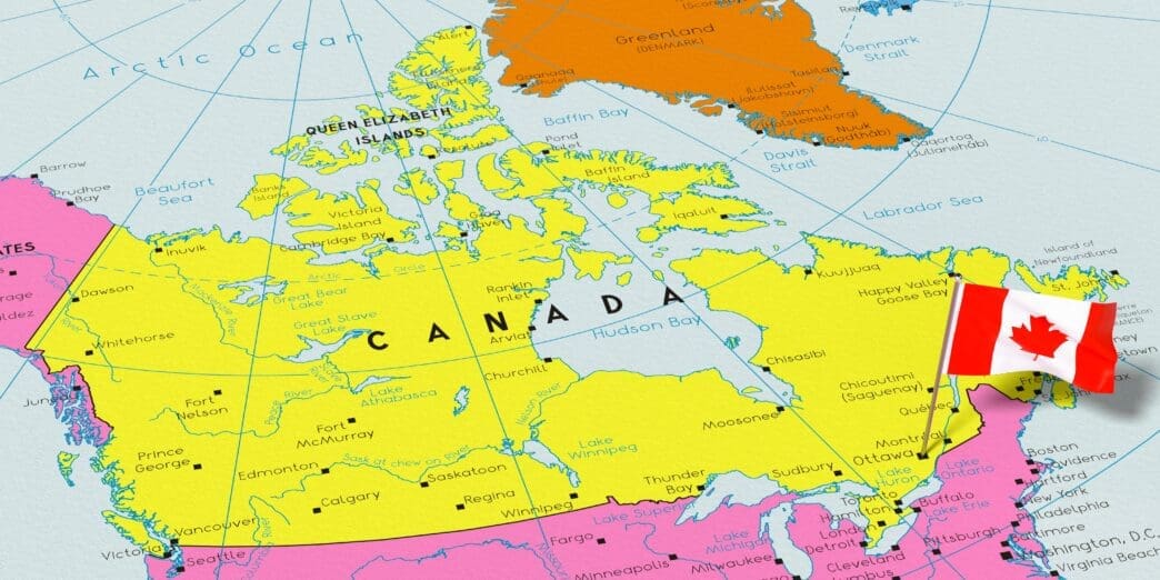 A colorful political map of Canada, highlighted in yellow, showing its provinces, territories, and major cities. A small 3D pin of the Canadian national flag is stuck into the map near the location of Ottawa.