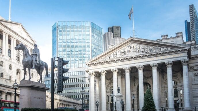A low-angle shot looking up at the grand, historical facade of the Bank of England in London, emphasizing its classical architecture and imposing columns.