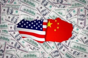 A conceptual image showing puzzle pieces shaped like the U.S. flag and the Chinese flag, fitted together in the center of a background made of scattered U.S. hundred-dollar bills.