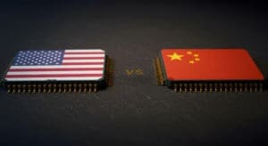 A conceptual image showing two computer microchips on a dark surface, facing each other. The chip on the left is decorated with the flag of the USA, and the chip on the right has the flag of China, with the letters "VS" between them.