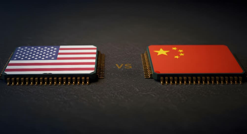 A conceptual image showing two computer microchips on a dark surface, facing each other. The chip on the left is decorated with the flag of the USA, and the chip on the right has the flag of China, with the letters "VS" between them.