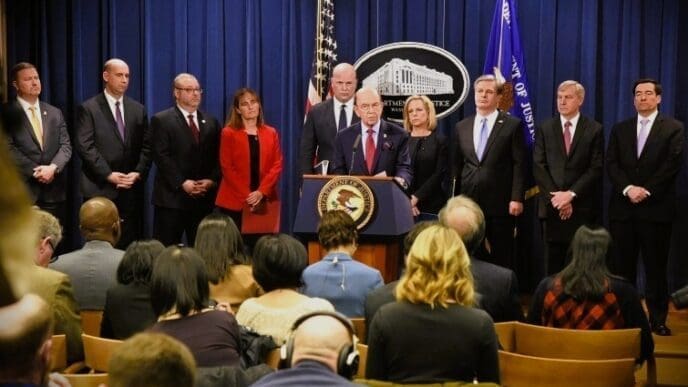 Then-U.S. Secretary of Commerce Wilbur Ross stands at a podium with the Department of Justice seal, speaking during a press conference announcing criminal charges against Huawei.
