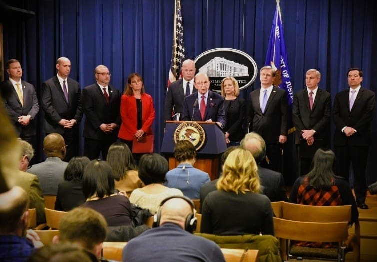 Then-U.S. Secretary of Commerce Wilbur Ross stands at a podium with the Department of Justice seal, speaking during a press conference announcing criminal charges against Huawei.