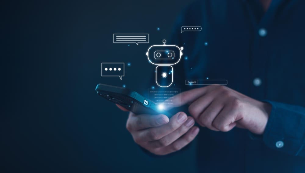 A person holding a smartphone with a glowing chatbot icon and chat bubbles floating above it, symbolizing AI interaction.