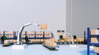 A clean, 3D-rendered scene of a futuristic warehouse with robotic arms and autonomous mobile robots (AMRs) moving and stacking cardboard boxes on conveyor belts and shelves.