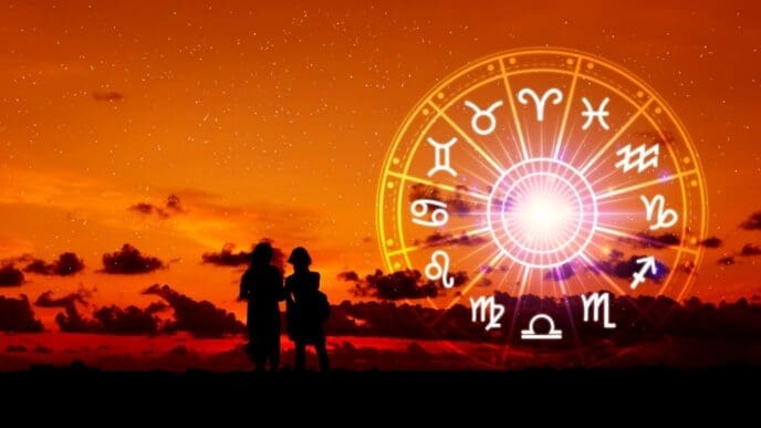 Silhouettes of two people standing before a glowing zodiac wheel against an orange, star-filled sunset sky with clouds.