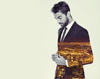 A double exposure image of a man in a suit, with a night cityscape superimposed onto his body, creating a conceptual representation of wealth, influence, or a deep connection to urban development.