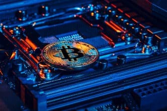 A gold Bitcoin coin rests on a computer motherboard, illuminated by blue and orange neon lights, symbolizing the intersection of cryptocurrency and advanced technology.