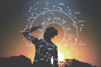 A silhouette of a person standing with one hand behind their head, overlaid with a luminous astrological chart featuring zodiac symbols and constellations, against a warm sunset or sunrise sky.
