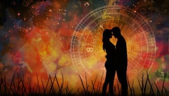 Silhouettes of a couple embracing in front of a glowing astrological birth chart, set against a vibrant, fiery cosmic background with grass in the foreground.