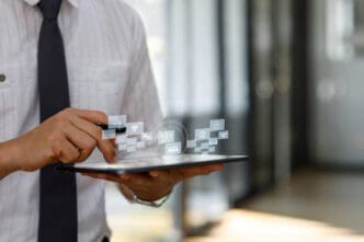 A businessman holding a tablet and interacting with floating holographic icons representing various digital services and data, symbolizing FinTech innovation.