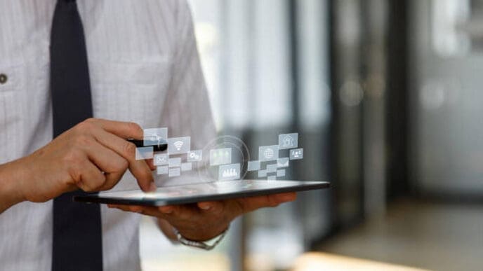 A businessman holding a tablet and interacting with floating holographic icons representing various digital services and data, symbolizing FinTech innovation.
