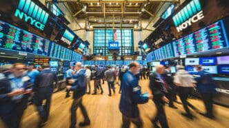 A bustling stock exchange trading floor with numerous traders, flashing digital displays, and an American flag.
