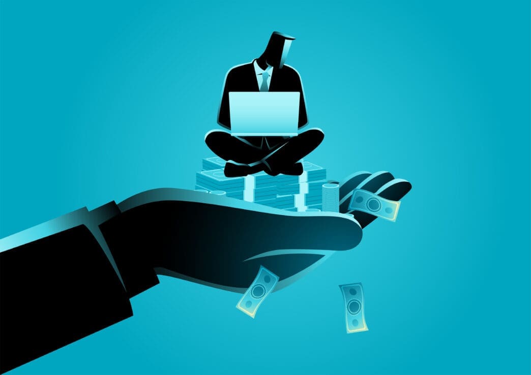 A large, dark silhouette of a hand extends forward, holding a smaller, silhouetted businessman sitting cross-legged on stacks of money, working on a laptop, against a vibrant blue background with falling money.
