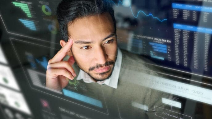 A man with a beard and dark hair, wearing a collared shirt, looks intently at multiple transparent digital screens displaying various graphs, charts, and data, representing complex FinTech tools.