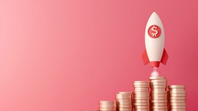 A 3D rendering of a white rocket with red fins and a dollar sign on its side, launching from a stack of golden coins, symbolizing rapid financial growth, all on a pink background.