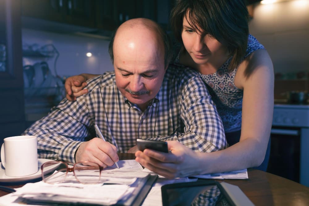 A concerned couple reviewing documents and a smartphone, appearing to manage finances.