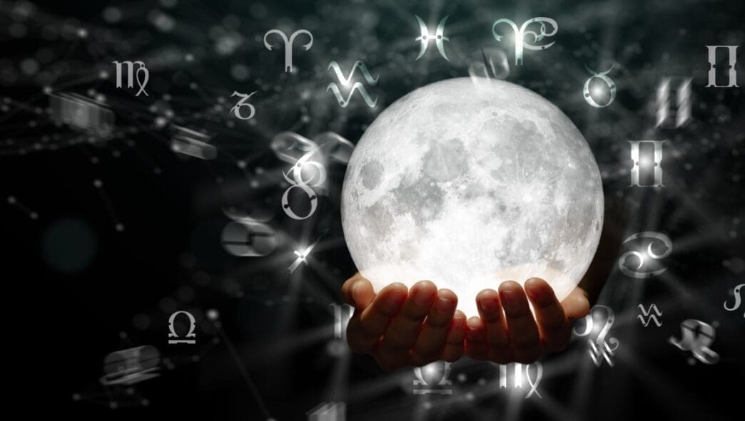 Two hands gently cradle a glowing full moon, surrounded by numerous floating white astrological zodiac and planetary symbols against a dark, ethereal, starry background with faint connected lines.
