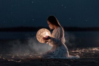 A young woman in a white dress kneels on a dark sandy surface at night, gently holding a glowing, textured sphere resembling the moon, with faint stars in the dark sky and a blurred body of water in the background.
