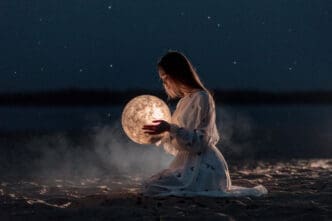 A young woman in a white dress kneels on a dark sandy surface at night, gently holding a glowing, textured sphere resembling the moon, with faint stars in the dark sky and a blurred body of water in the background.