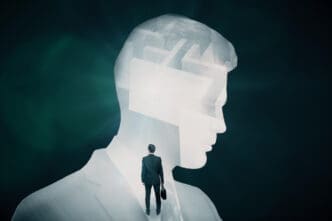 A silhouette of a businessman walking into a large, transparent head that contains a labyrinth, symbolizing complex thought and risk.