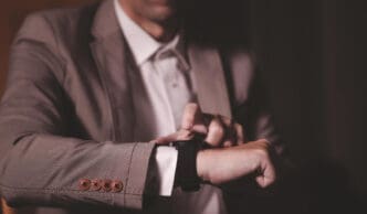 A man in a suit checking or interacting with his smartwatch, indicating time management.