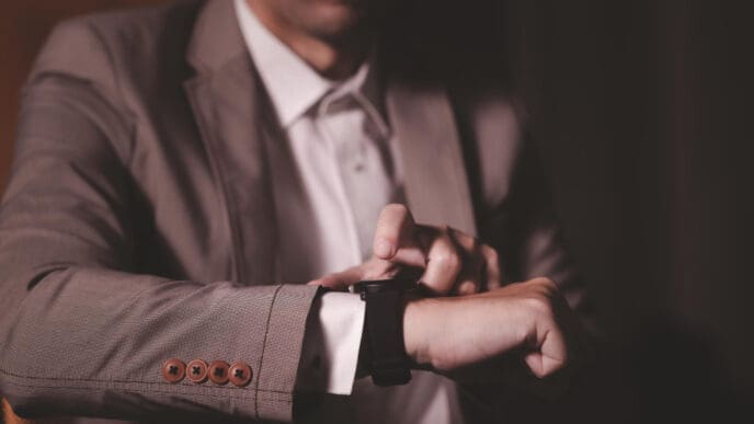 A man in a suit checking or interacting with his smartwatch, indicating time management.