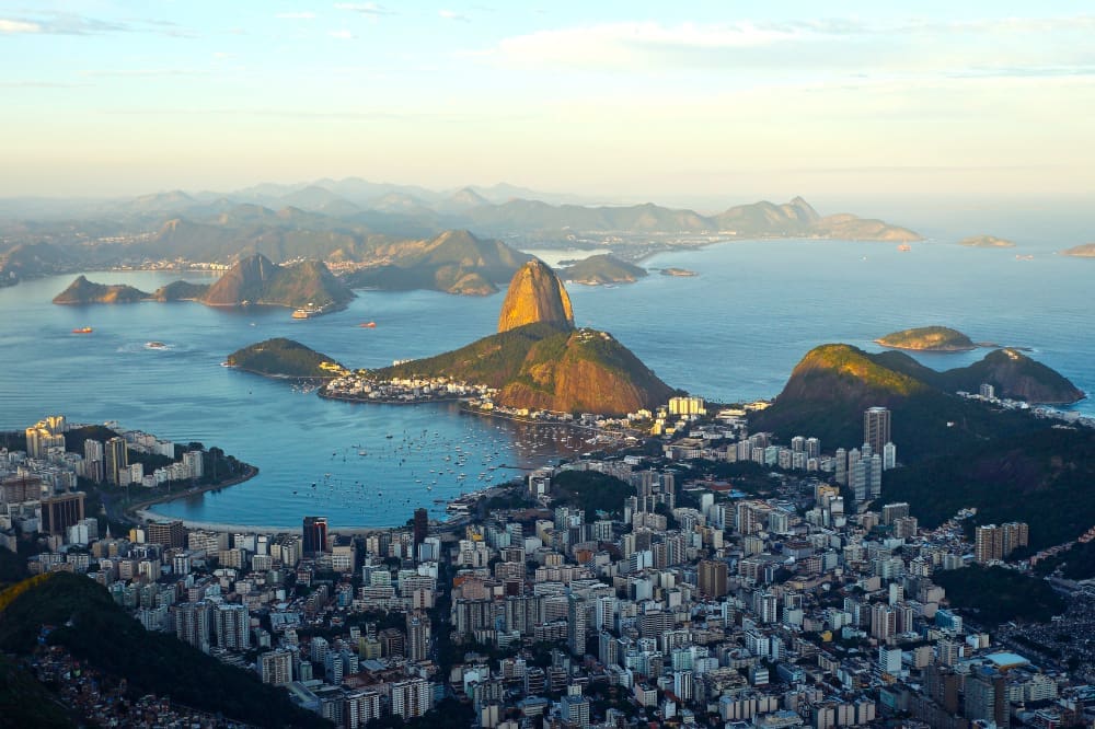 Aerial panoramic view of Rio de Janeiro, Brazil, featuring Sugarloaf Mountain, Guanabara Bay, and the sprawling city.