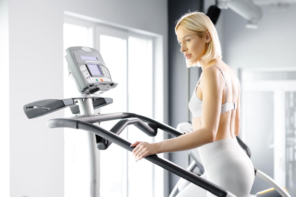 A young woman in sportswear working out on a stairway simulator at the gym.