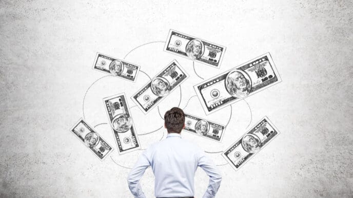 A man seen from behind, looking up at sketched dollar bills connected by lines on a concrete wall, symbolizing financial strategy.