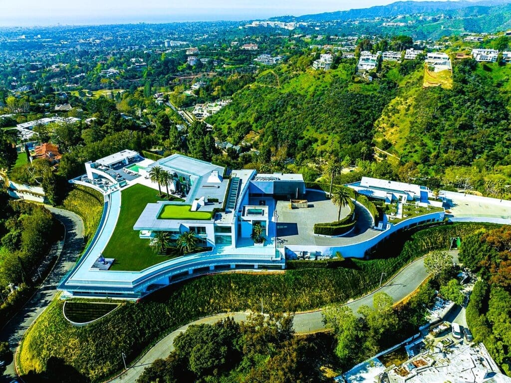 Aerial view of "The One" mansion in Bel Air, California, a massive modern estate with multiple levels, pools, and extensive grounds, nestled in green hills.