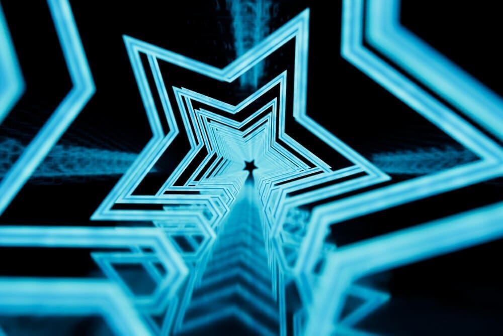 A tunnel of glowing star patterns stretches across a black background.