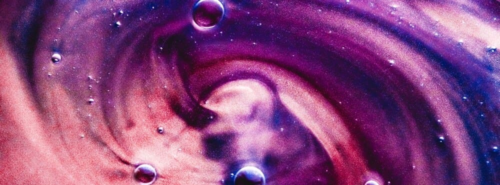 Abstract banner with swirling paint splashes, water drops, and a gel-like texture.