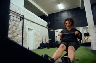 An African American woman uses a rowing machine during a CrossFit workout.