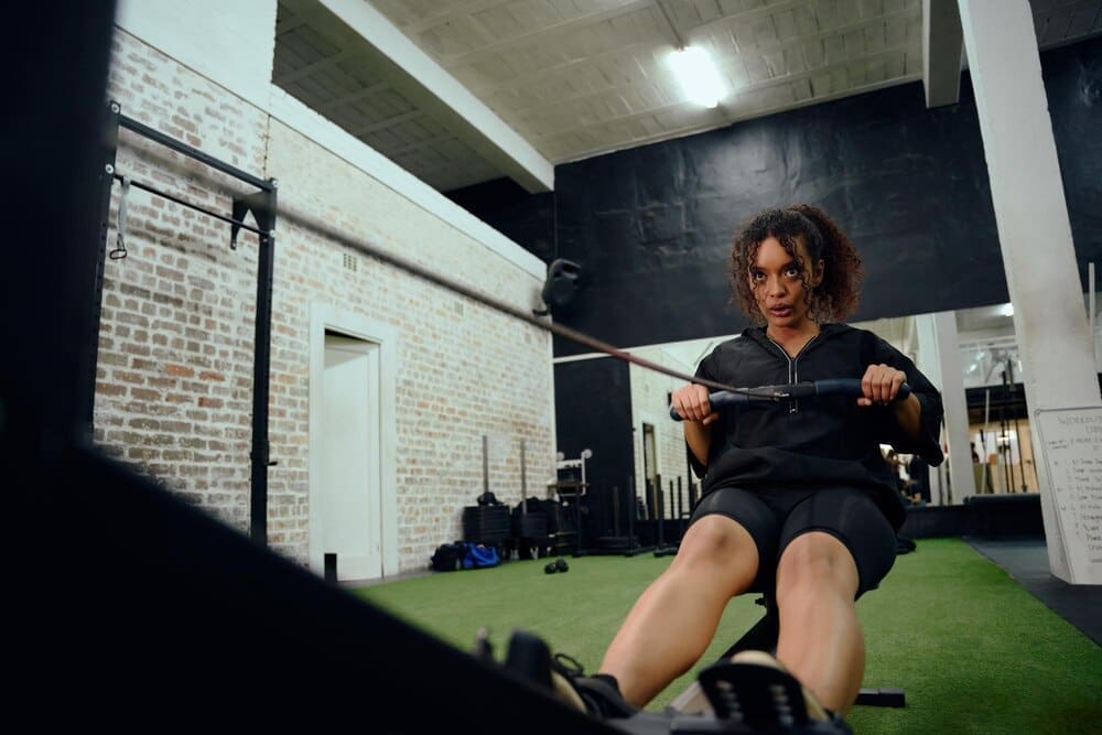 An African American woman uses a rowing machine during a CrossFit workout.