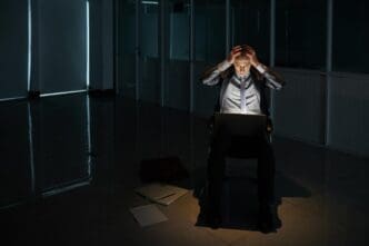 A businessman with his head in his hands appears dejected after a negotiation.