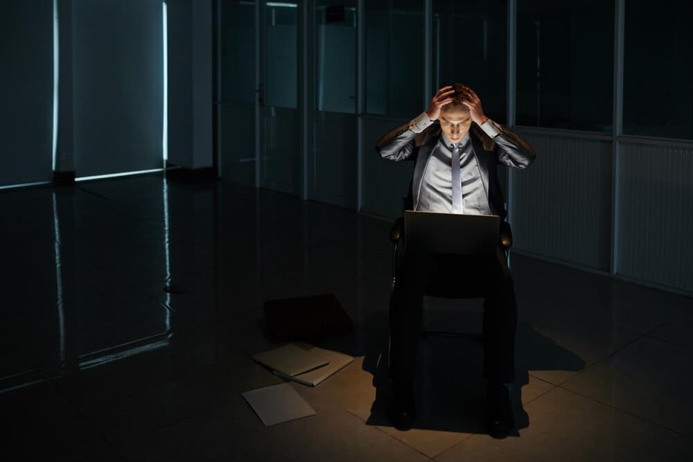 A businessman with his head in his hands appears dejected after a negotiation.