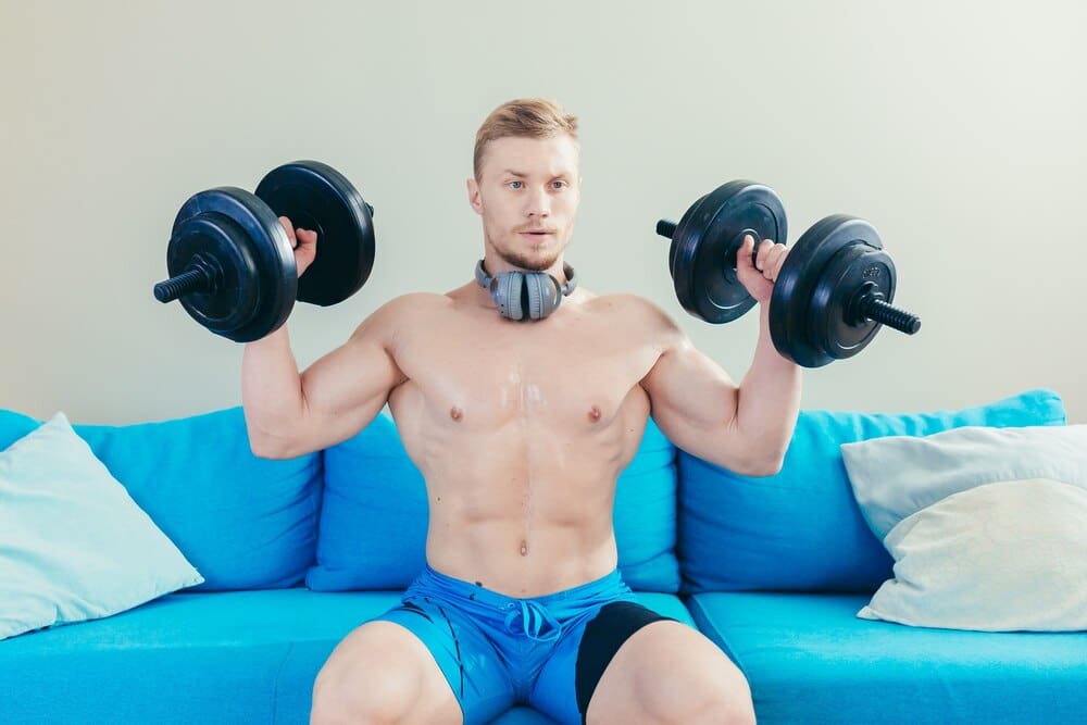 A person at home uses dumbbells while exercising.